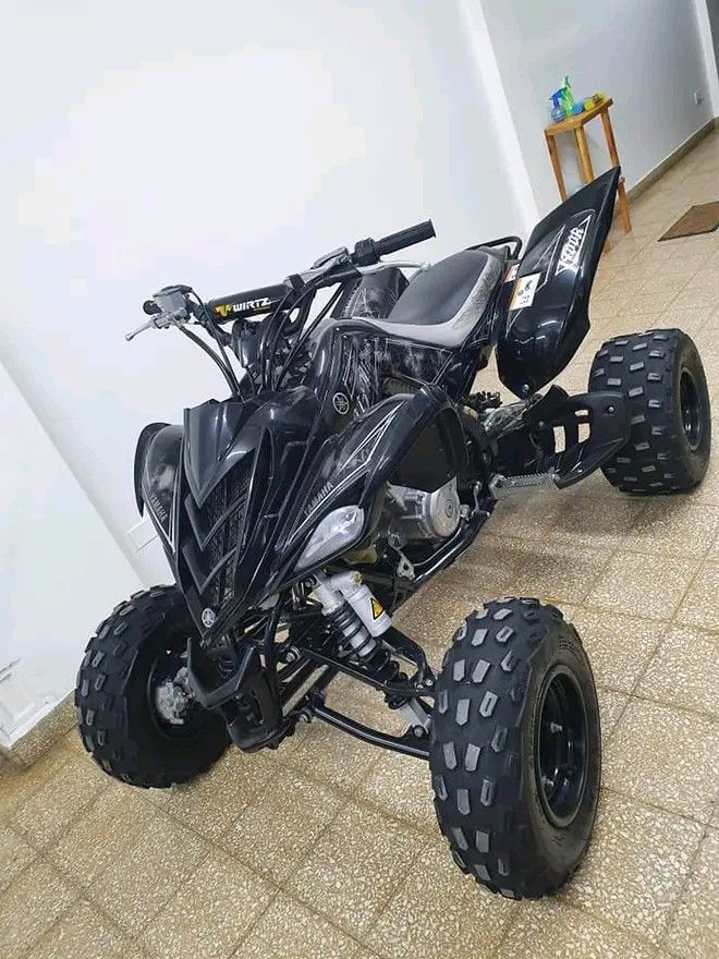 a black four - wheeler is parked on the floor in front of a white wall