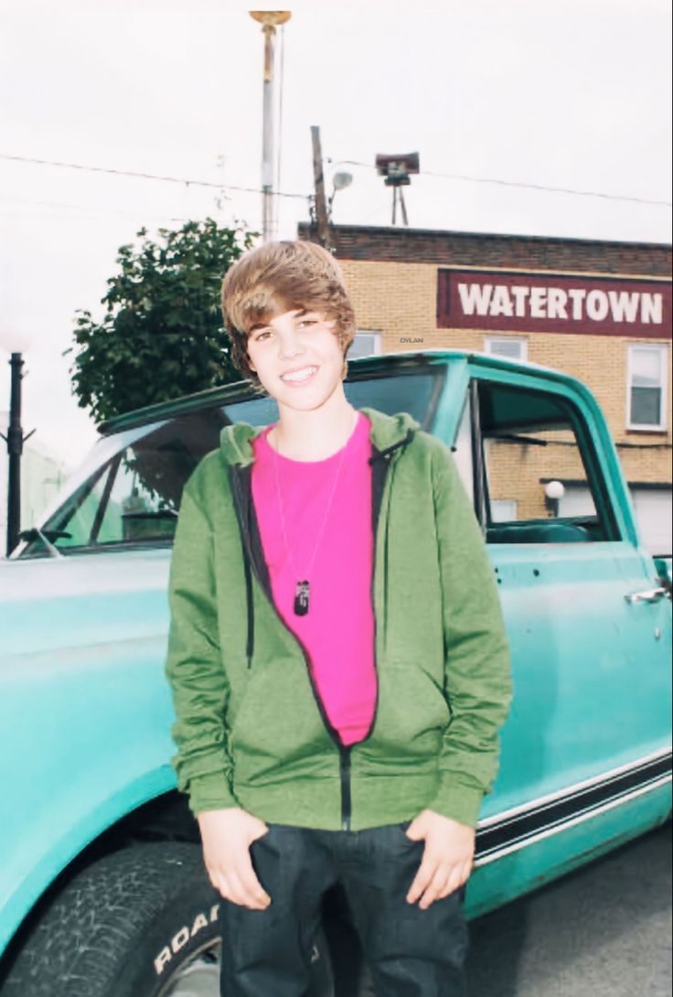 a young man standing in front of a blue truck