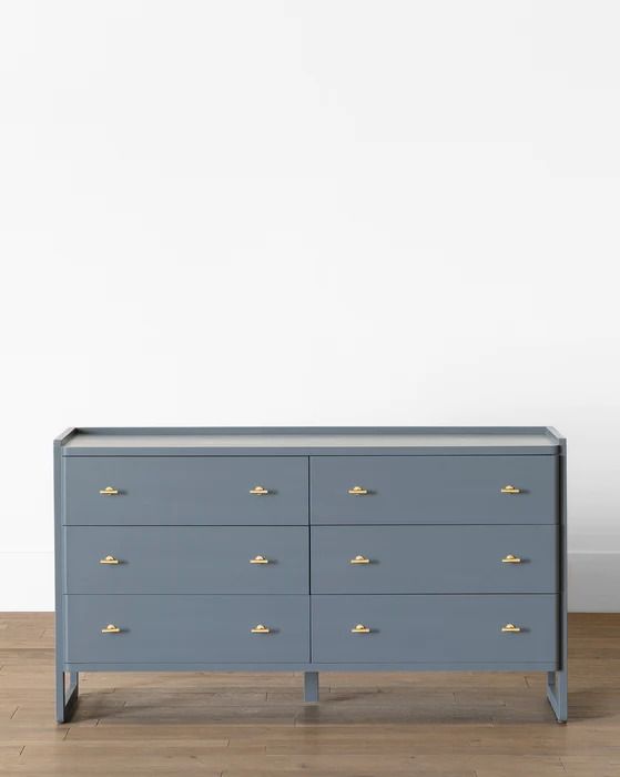 a blue dresser sitting on top of a hard wood floor next to a white wall