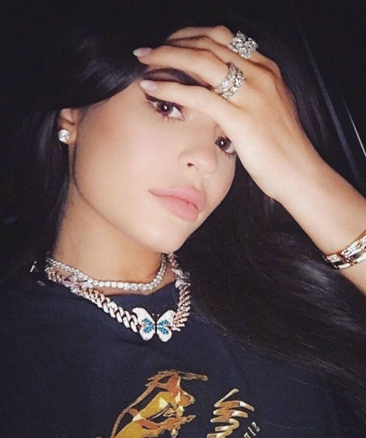 a woman in black shirt holding her hand to her head with two rings on it