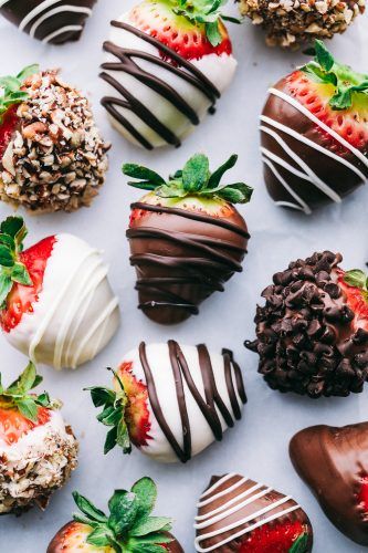 chocolate covered strawberries are arranged on a white surface