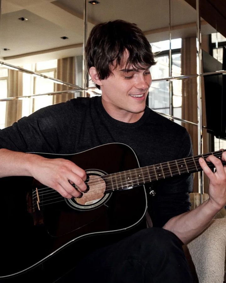 a young man is playing an acoustic guitar