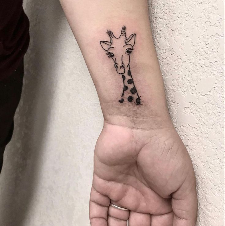 a small giraffe tattoo on the left wrist is shown in black and white