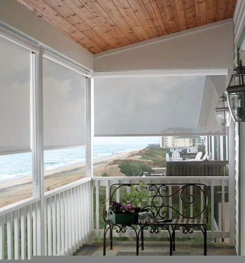 a balcony with an iron table and bench on the front porch next to the ocean