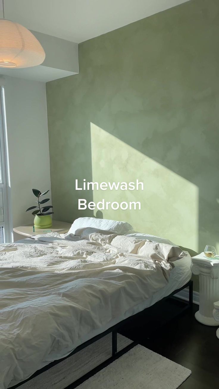 an unmade bed sitting in a bedroom next to a tall window with the words limewash bedroom on it