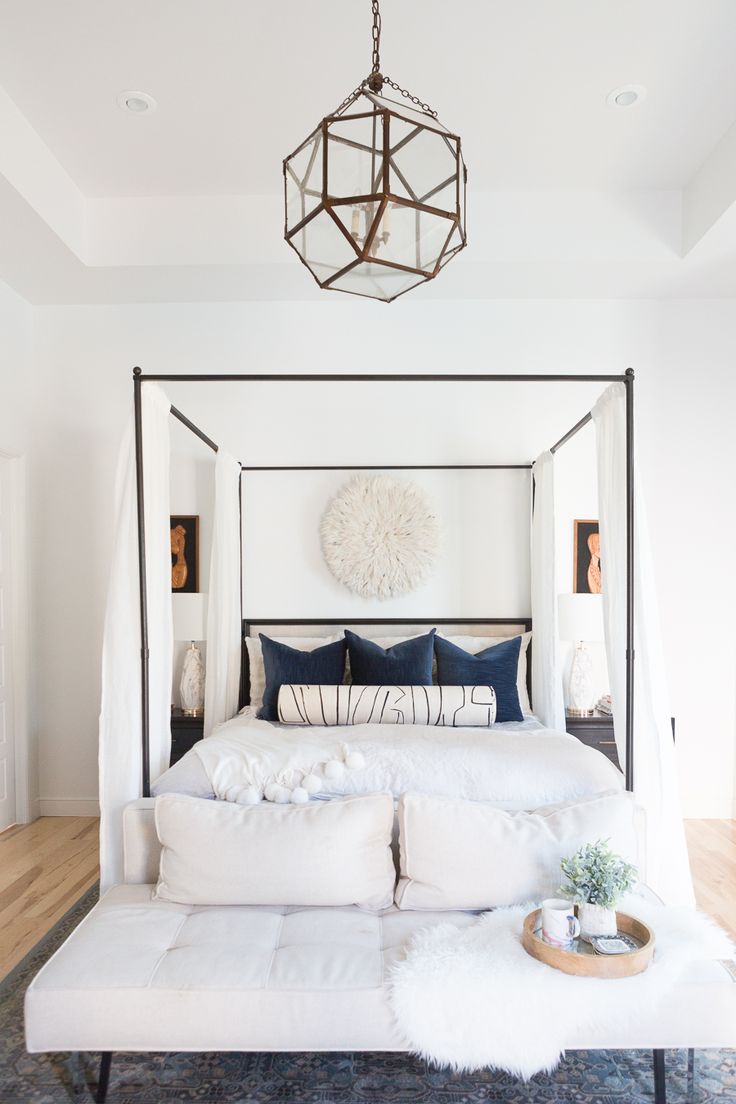 a bedroom with a canopy bed, rug and pink flowers in vases on the floor