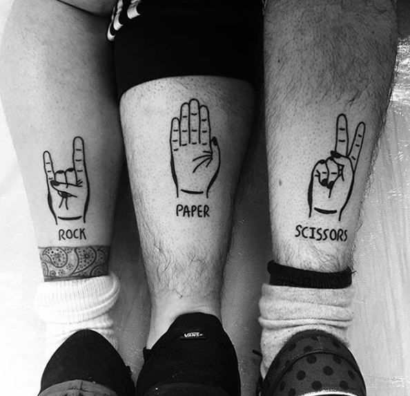 two people with matching tattoos on their legs are holding up the word paper and scissors