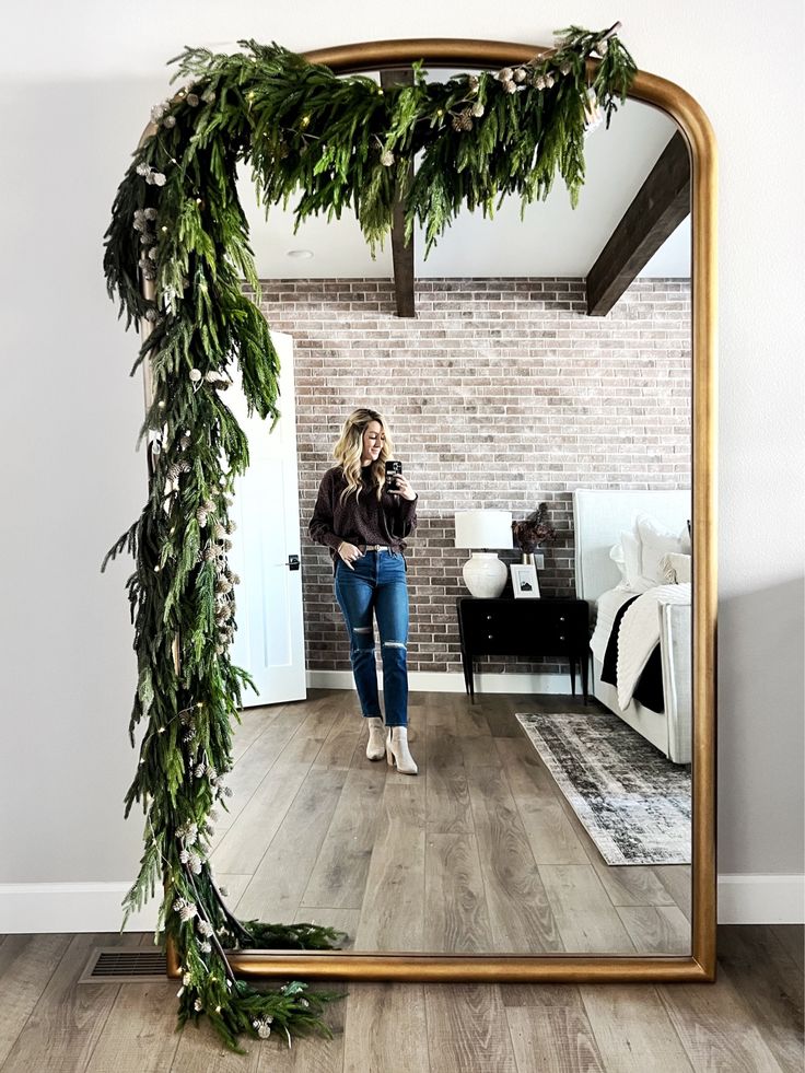 a woman taking a selfie in front of a mirror with greenery on it