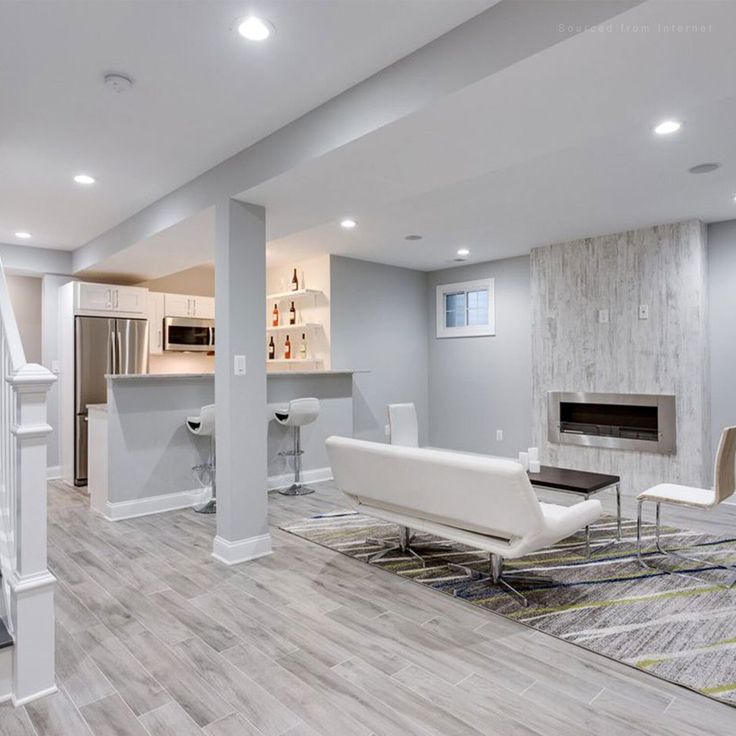 a living room filled with furniture and a fire place next to a kitchen on top of a hard wood floor