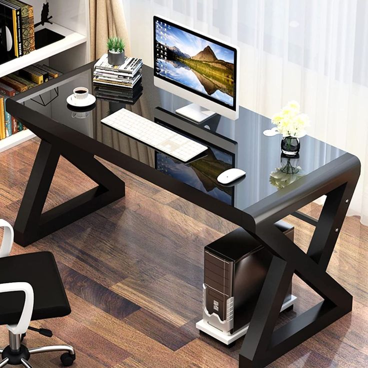 a computer desk with a monitor and keyboard on top of it, in front of a window