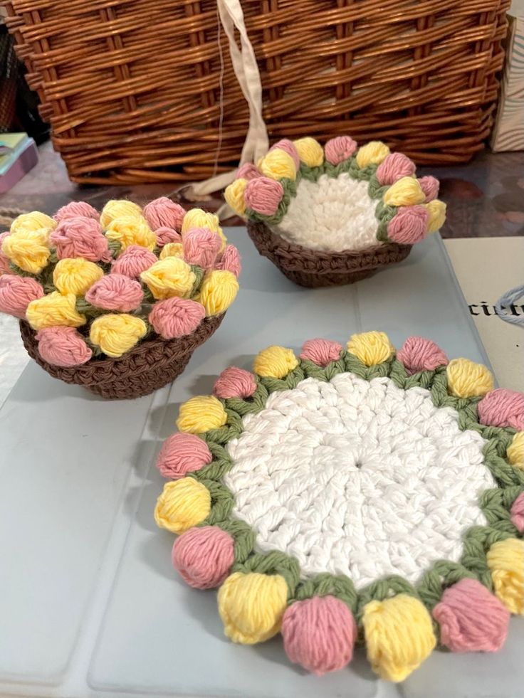 crocheted baskets with flowers in them sitting on a table next to a basket