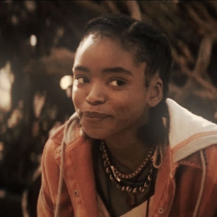 a young man with dreadlocks sitting in front of a tree