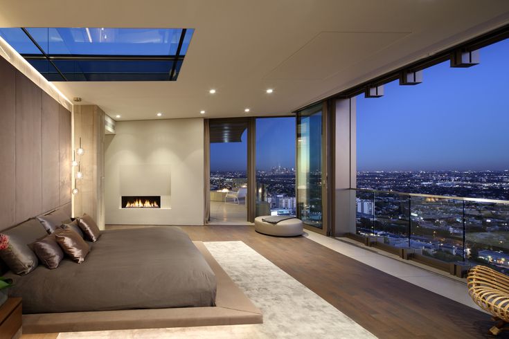 a bedroom with a large bed and floor to ceiling windows looking out onto the city