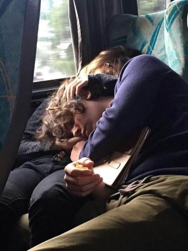 two people are sleeping on a bus together