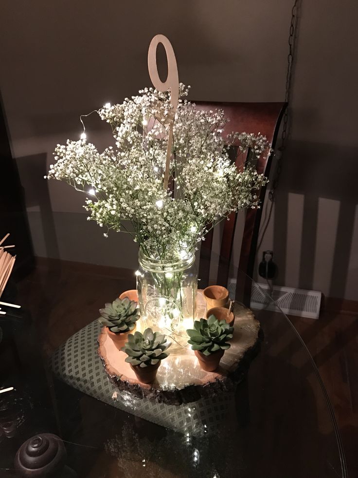 a vase with flowers on top of a table next to a basket filled with succulents