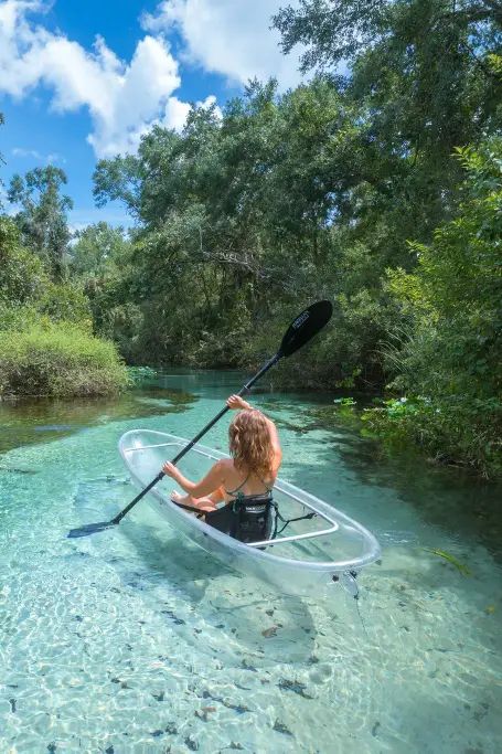 a woman in a kayak paddling through shallow water