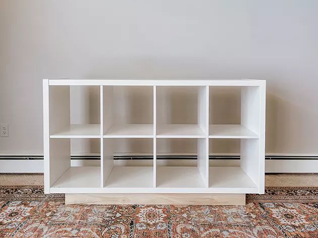 a white shelving unit sitting on top of a rug in front of a wall