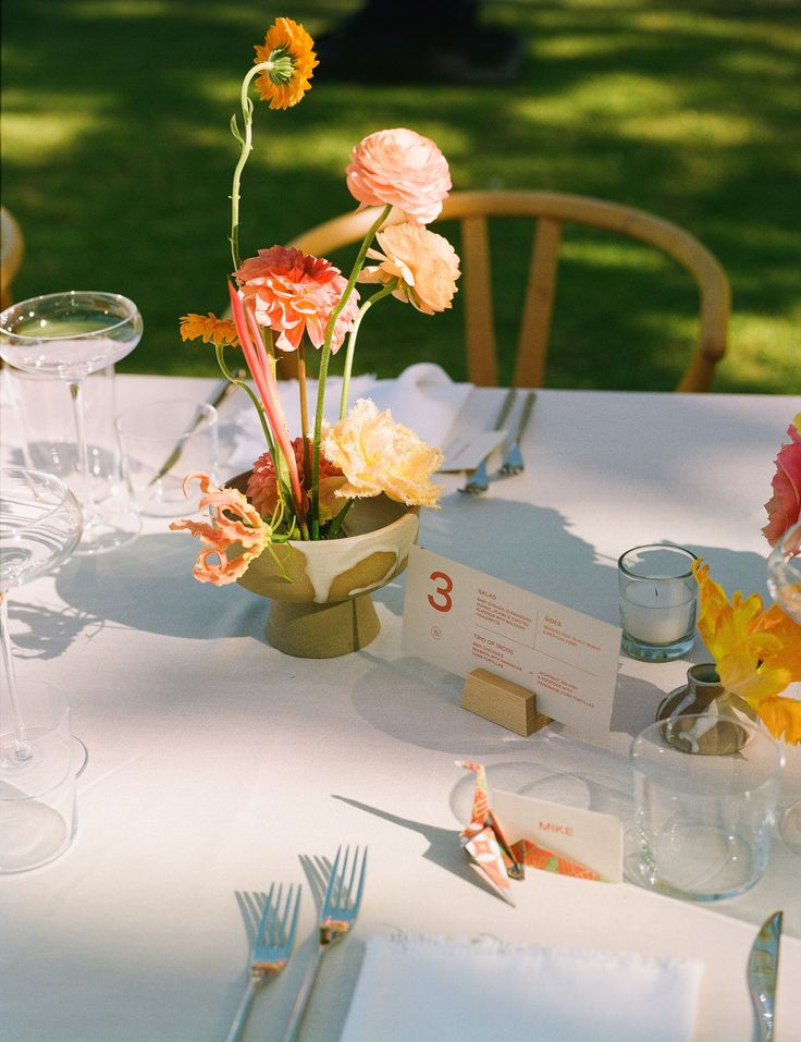 the table is set with flowers and place cards for guests to sit down at it