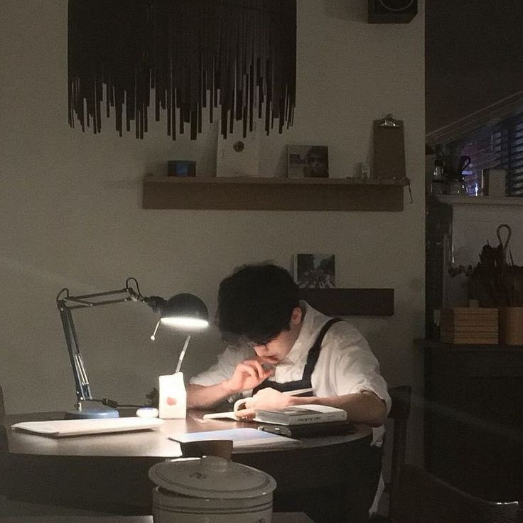 a man sitting at a desk in front of a laptop computer with a lamp on top of it