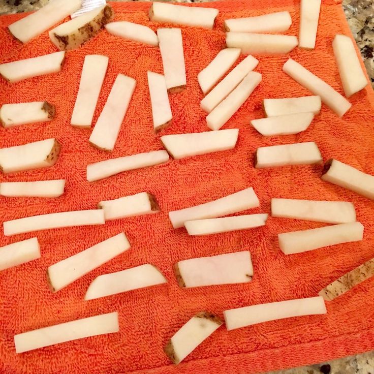 an orange towel with several pieces of cheese cut up on it and some knives in the background