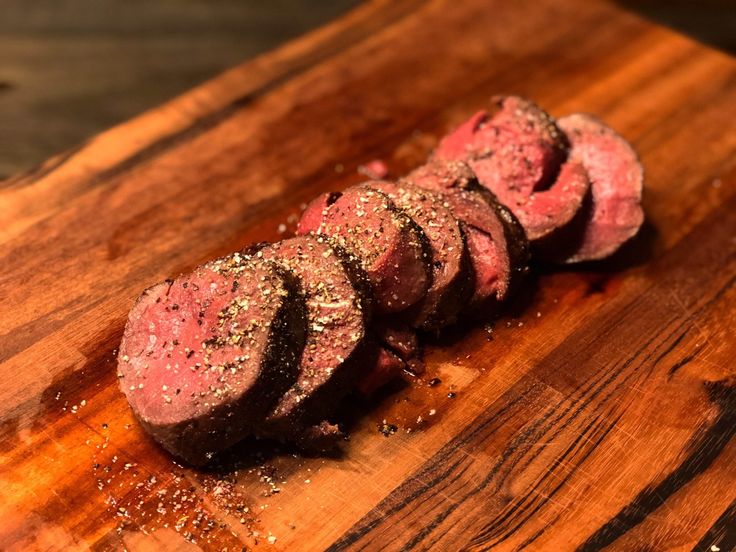 sliced up meat on a cutting board with seasoning sprinkled around it's edges