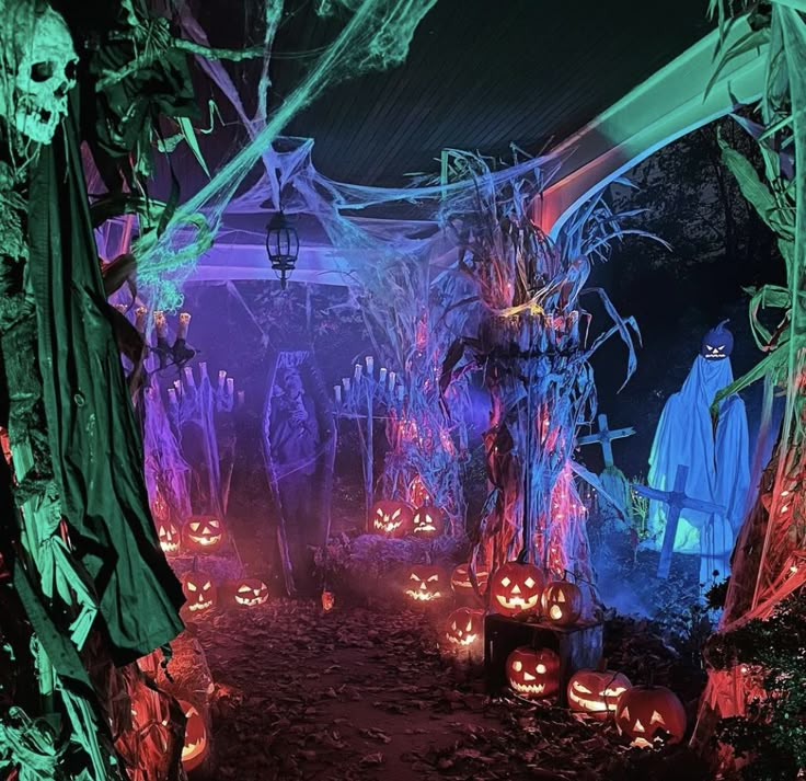 an outdoor halloween scene with carved pumpkins and ghost statues in the background, all lit up by colorful lights