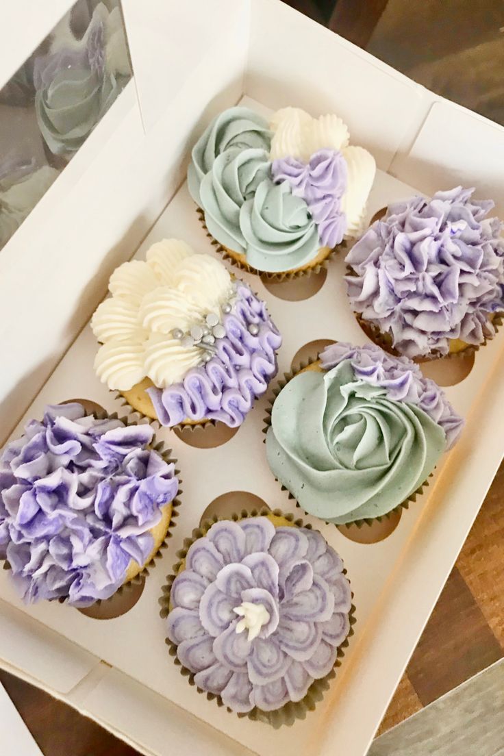 six cupcakes in a white box with purple and blue frosting