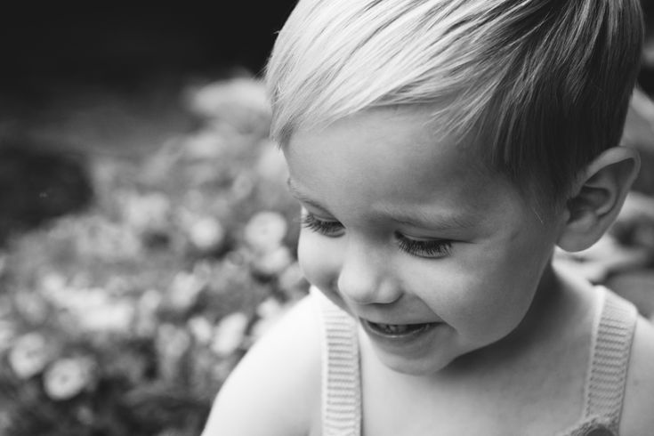 a little boy that is standing in the grass with a cell phone to his ear