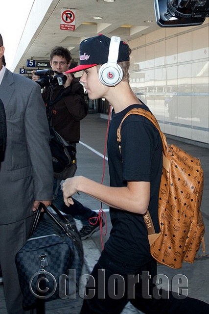 Justin Bieber toting MCM Cognac Visetos Backpack    Justin Bieber spotted arriving at LAX with Beats by Dr. Dre Pro over the ear headphones and carrying a Cognac Visetos MCM Backpack    Availble with or without studs, what is the difference, around £325    *courtesy of UK's exclusive luxury authentic handbag SPA Visit us on Facebook: www.facebook.com/DelortaeAgency Mcm Backpack Outfit, Justin Bieber 2011, Mcm Bag, Mcm Backpack, Backpack Outfit, Mcm Bags, Handbag Outlet, Handbags Michael Kors