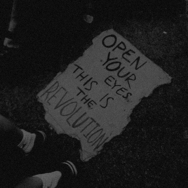 a sign on the ground that says open your eyes this is the revolution written on it