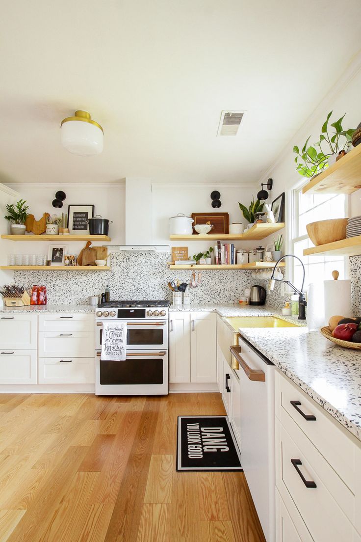 a kitchen with white cabinets and wooden floors, open shelves on the wall above the stove