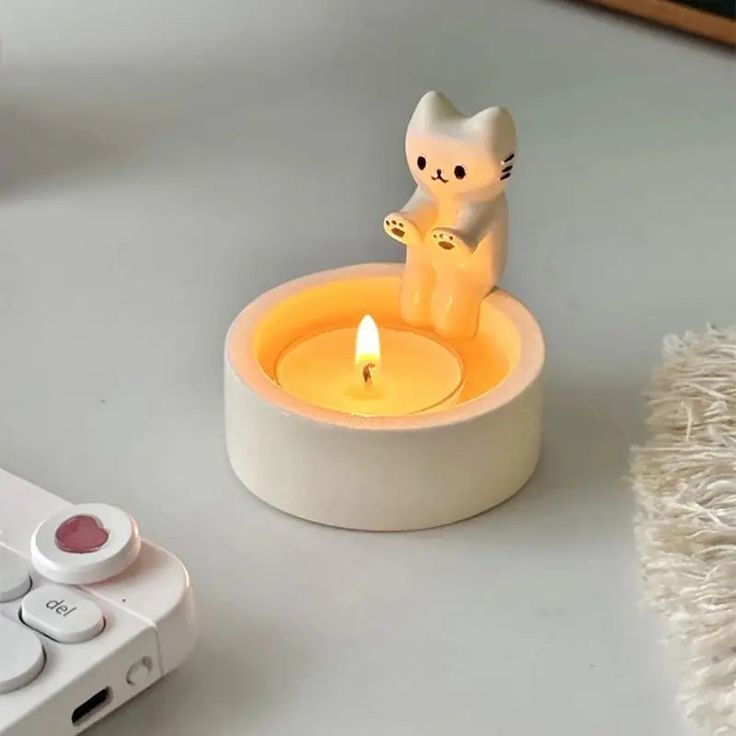 a cat figurine sitting on top of a table next to a remote control