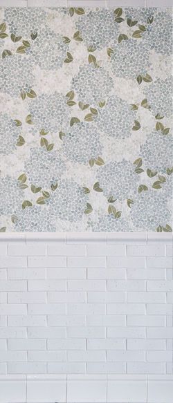 a white brick wall with green leaves on it