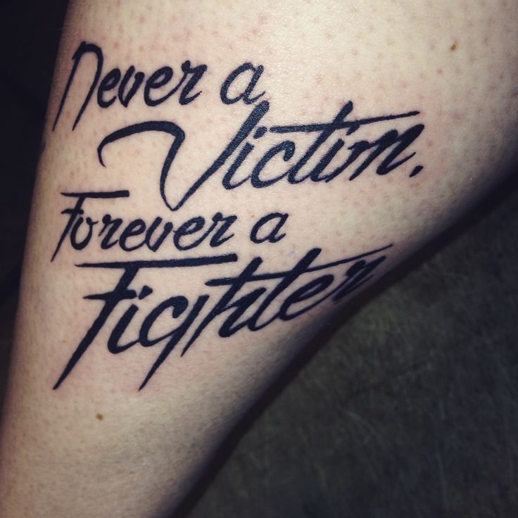 a tattoo that says never a victim forever a fighter on the leg, with black ink