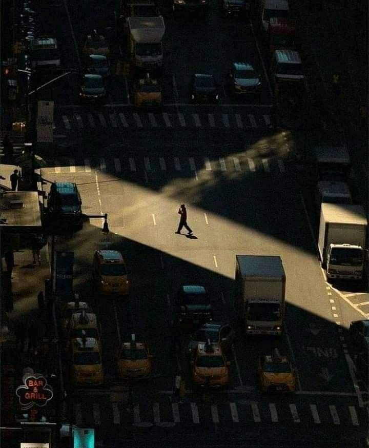 a person walking across a street in the middle of traffic at night with cars and trucks