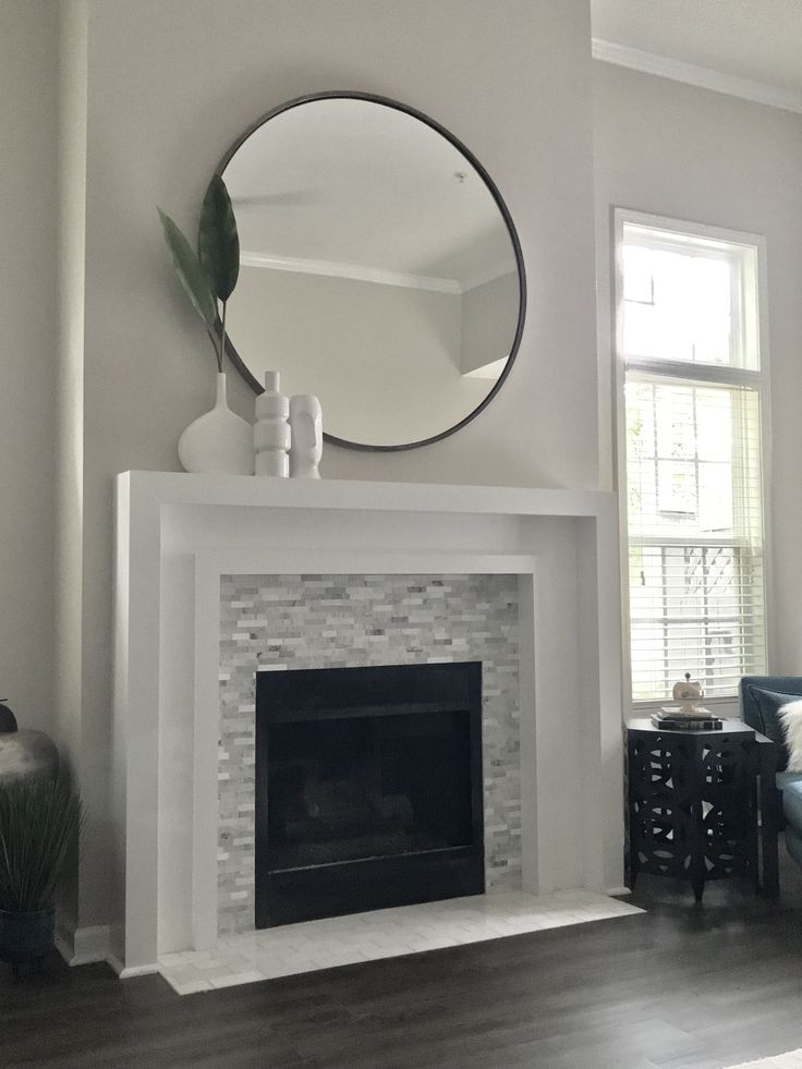 a white fireplace with a mirror above it