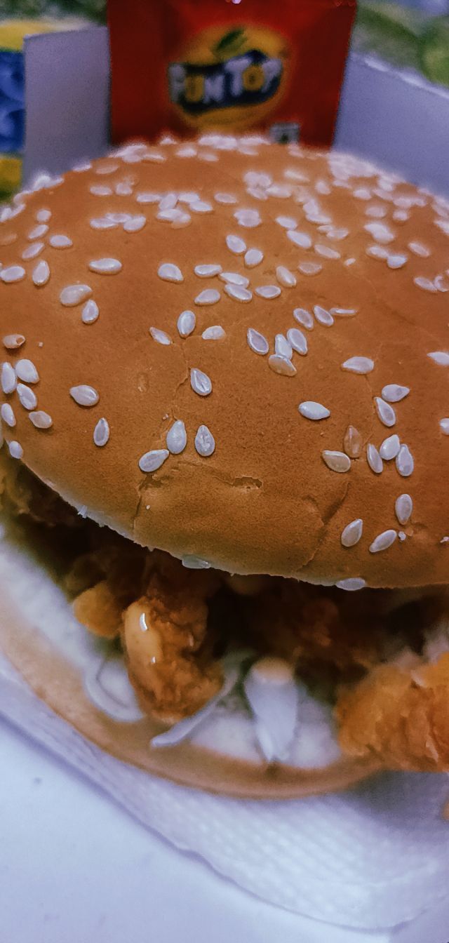 a chicken sandwich with onions and mayonnaise on a plate next to a box of chips