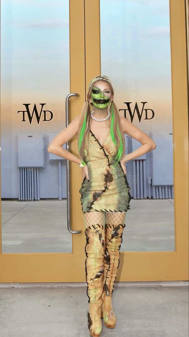 a woman with green hair is standing in front of a door