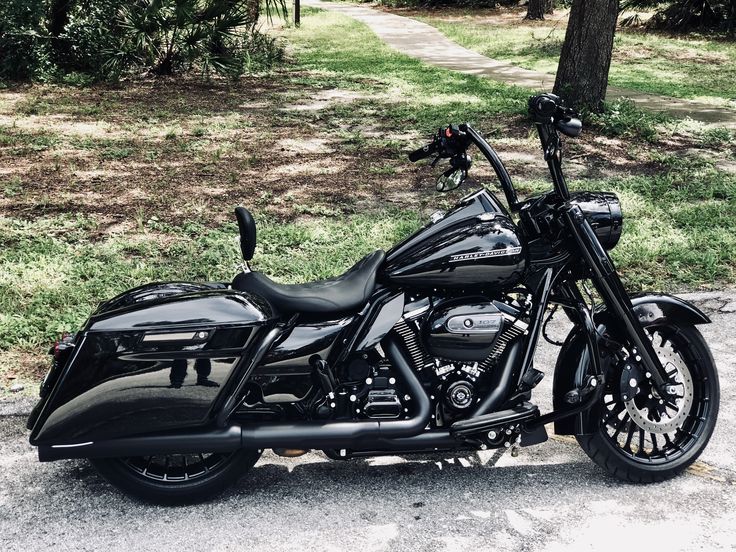 a black motorcycle is parked on the side of the road in front of some trees