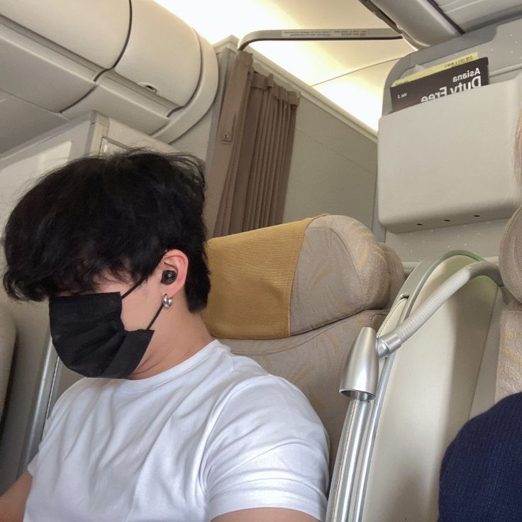 a man wearing a face mask while sitting on an airplane