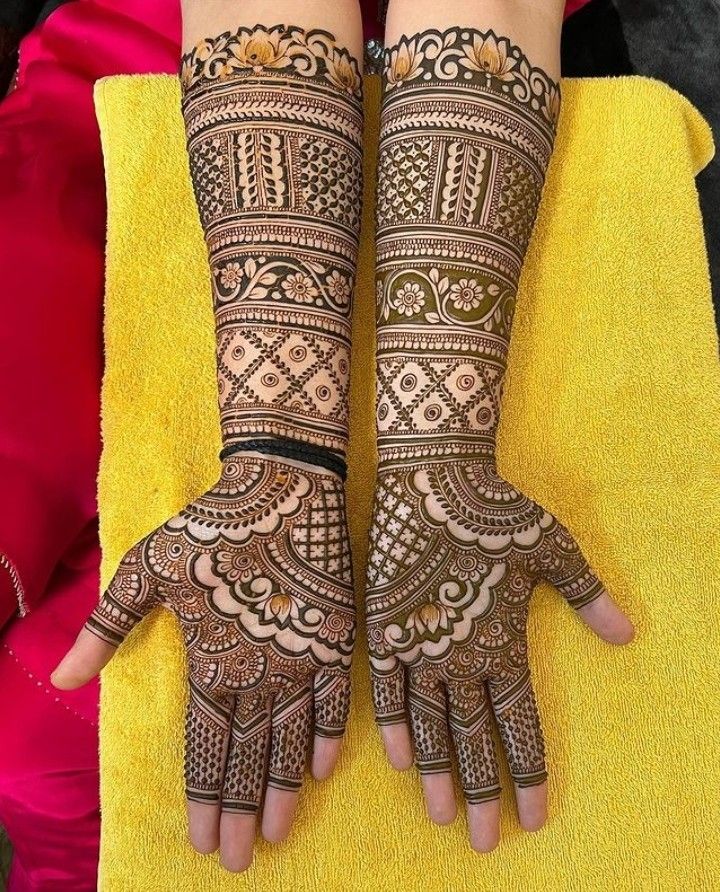 two hands with henna tattoos on them sitting next to each other and yellow towels in the background