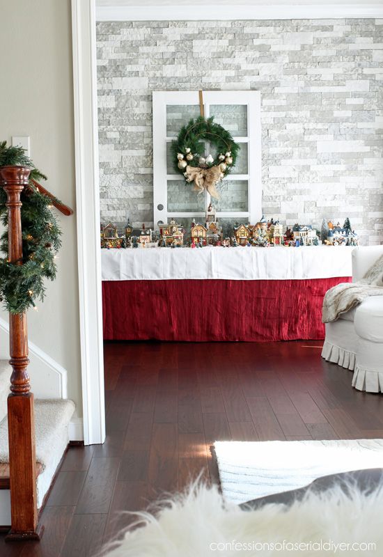 a living room filled with furniture and a christmas wreath on top of the fireplace mantel