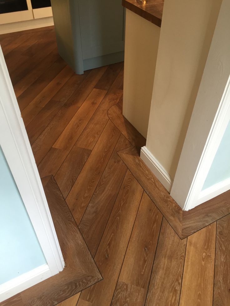 an empty kitchen with wood flooring and white trim on the walls, next to a counter