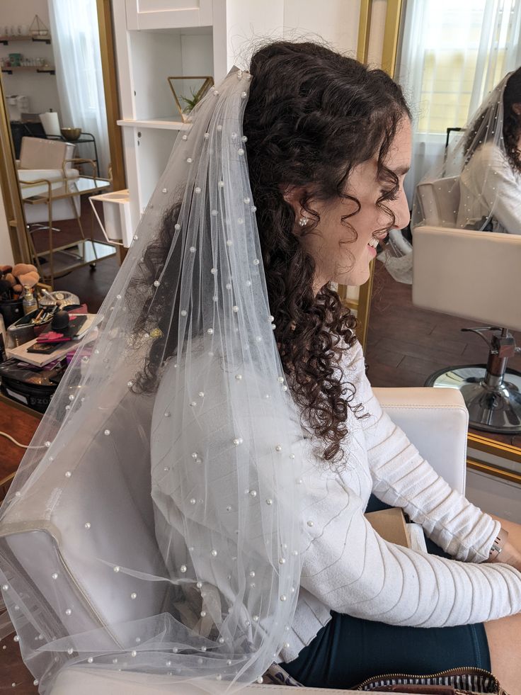 a woman sitting in front of a mirror wearing a veil