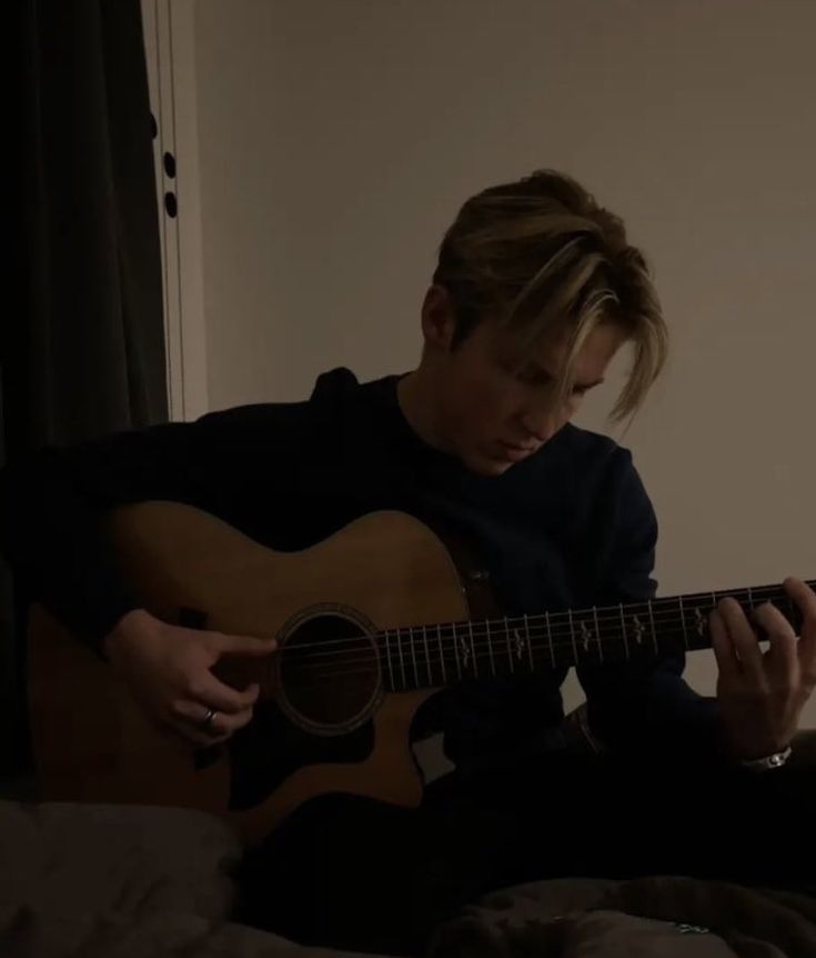 a person sitting on a bed playing a guitar