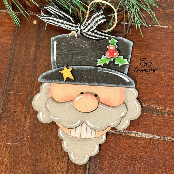 a christmas ornament hanging from a tree on a wooden floor with pine branches