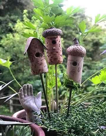 three bird houses in a potted plant with hands and fingers sticking out from them