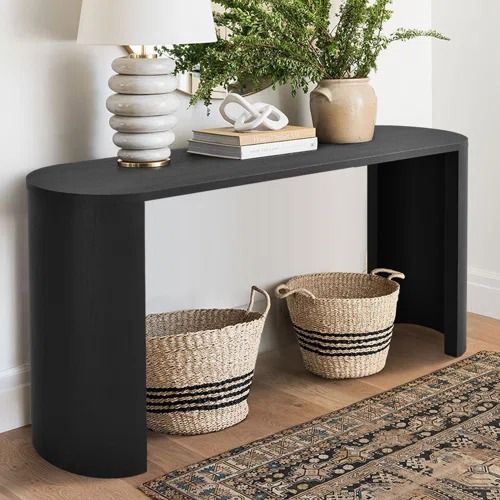 a black console table with two baskets on top and a lamp next to it in the corner