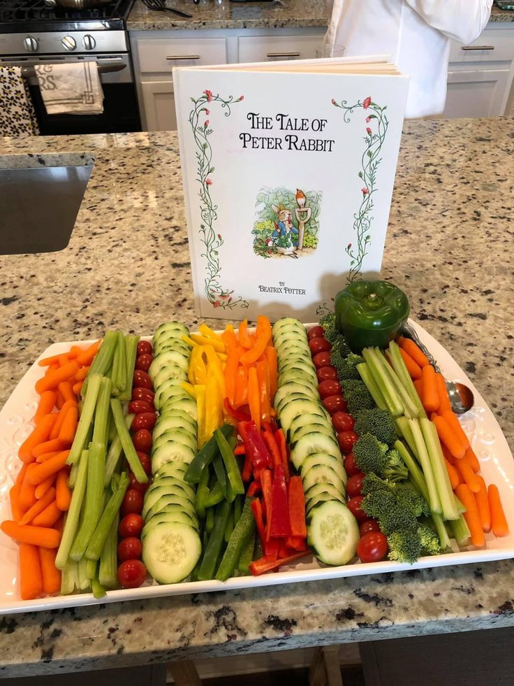 a platter filled with lots of veggies next to a book on top of a counter