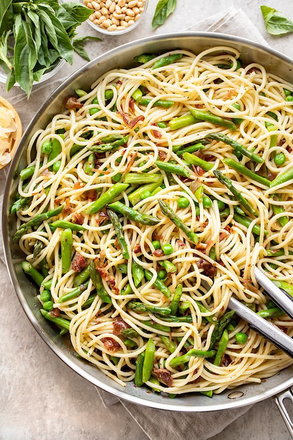 a pan filled with pasta and asparagus on top of a table next to other ingredients